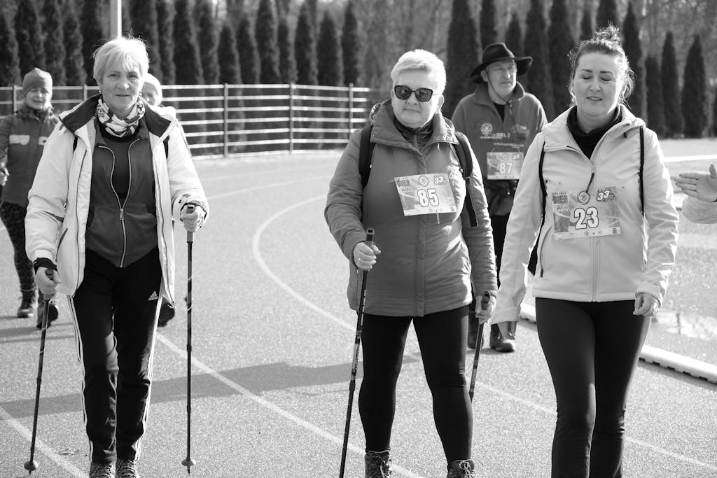 Adults walking with poles on a track during a daytime outdoor event.